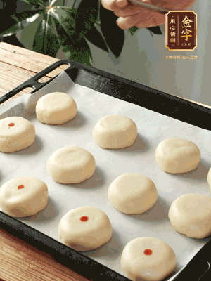 收口向下放在案板上，輕輕將月餅坯按扁，用筷子點紅點做裝飾