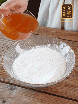 轉(zhuǎn)化糖漿、枧水、花生油攪拌均勻，加入面粉混合，醒發(fā)2小時(shí)。捏成23g一個(gè)的小球